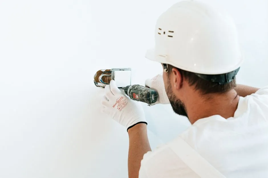 Deux artisans discutant sur un chantier avec outils, plans et cloisons en cours de rénovation
